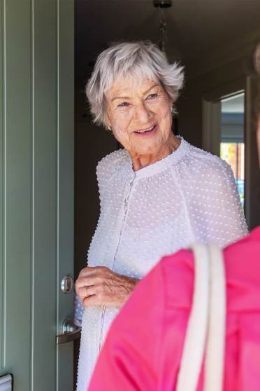 Woman opening front door to carer