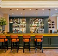 Stools at a long, well stocked bar