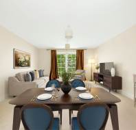 A modern living and dining room with a dark wooden table set for four, a beige sofa, TV on a stand, large window with brown curtains, and artwork on the walls.