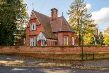 A red-brick Victorian house with a steep roof is surrounded by a brick wall and trees. A sign reading "Abby Lodge, Kew Bridge" is visible in the foreground.