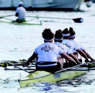River stories Four rowers in matching outfits compete in a rowing event, gliding through the water in a yellow boat.