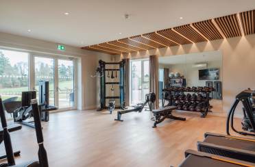 Fully equipped gym and fitness studio A modern gym with exercise machines, weights, and workout benches. Large windows and a mirrored wall enhance the spacious interior.