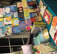 A display table with a variety of colorful children's books arranged on shelves and laid flat, featuring titles about animals, Christmas, and educational topics.