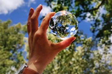 Earth Day Blue sky through a glass ball in hand